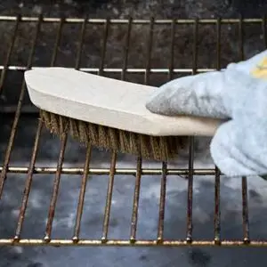 Grillrost, der durch eine Grillbürste gereinigt wird